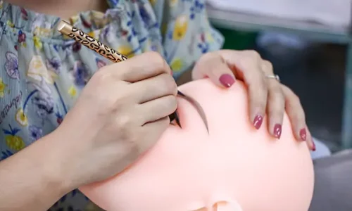 applying makeup to a doll’s eyebrows